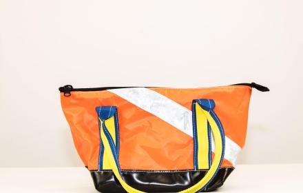 Right side of bag. Orange with silver strap and yellow and blue handles.